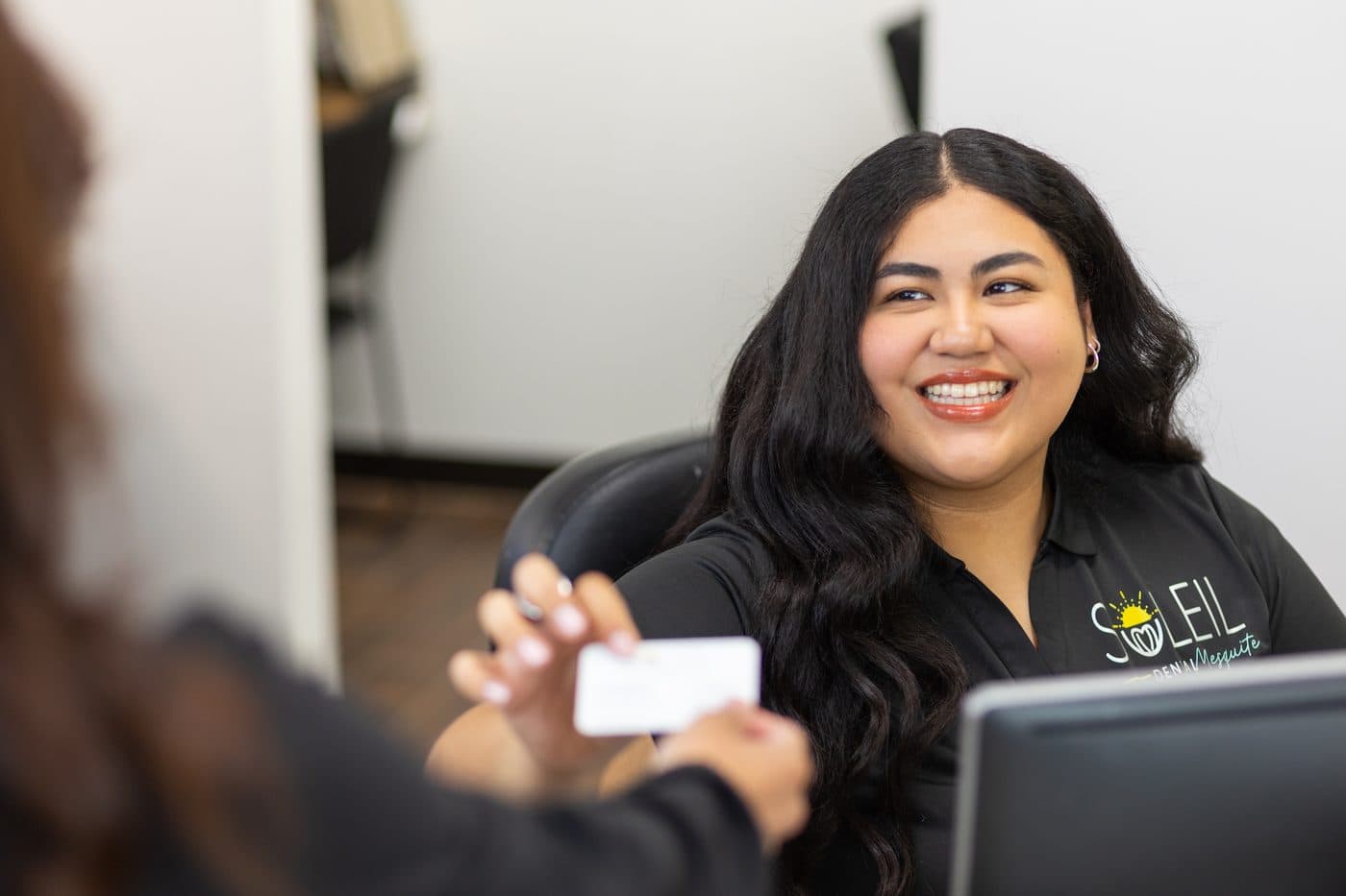 A smiling front desk team member handing a card back to a patient