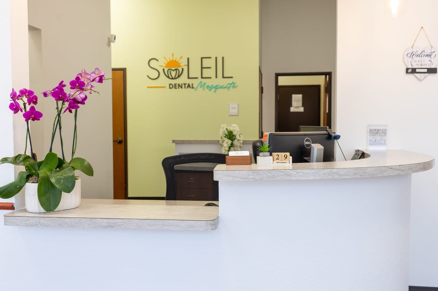 La recepción de Soleil Dental Mesquite con orquídeas y el muro verde del logo