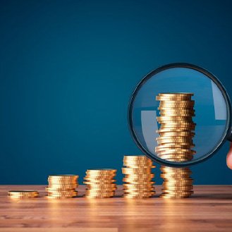Magnifying glass looking at increasingly taller stacks of coins