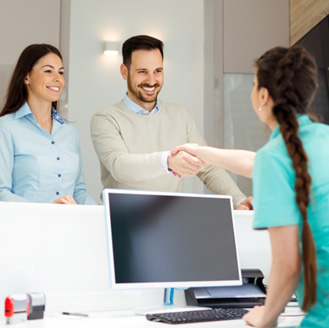 Dental team member shaking hands with a patient at the front desk