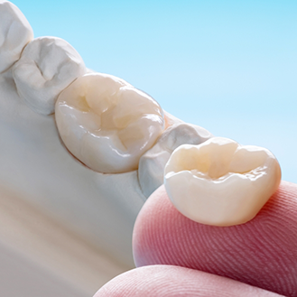 Close up of a dental crown resting on a finger