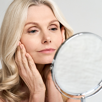 Woman touching her face and looking in the mirror