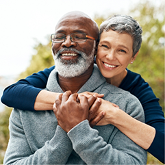 Senior couple hugging in front of green trees