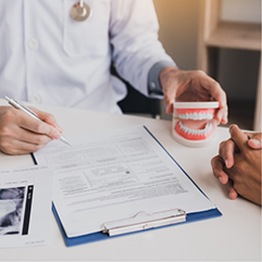 Dental patient sitting across a desk from their dentist during a consultation