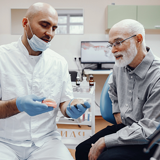 Dentist showing dentures to a senior man in the dental chair