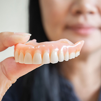 Dental professional holding a full upper denture