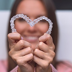 Woman holding clear aligners in heart shape