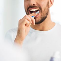 Man in white t-shirt brushing teeth