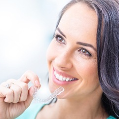 Woman smiling holding Invisalign to her mouth