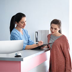 Dental team member showing a patient where to sign on a clipboard