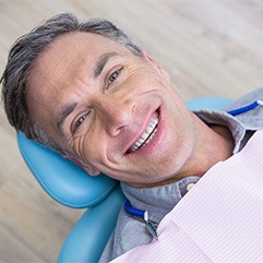 Man lying back in dental chair and smiling