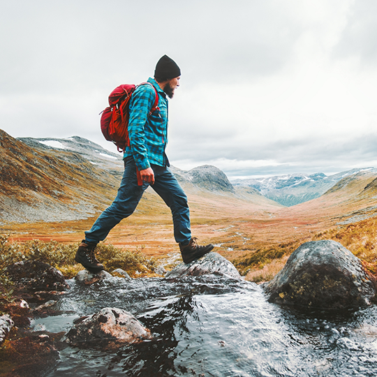 Bearded man in hiking gear walking through a valley between two mountains