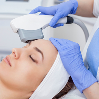 Dentist applying a laser device to a womans forehead