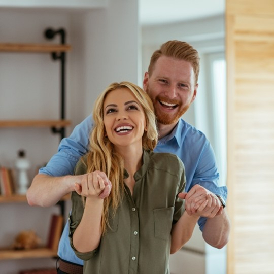 Man and woman smiling and holding hands in their home after orthodontics in Mesquite