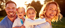 Family of four smiling in the sun