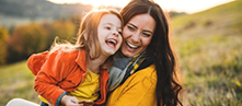 Mother holding her child and laughing outdoors