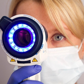 Dentist holding a scope with a blue light around the lens