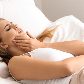 Woman lying in bed, experiencing a toothache