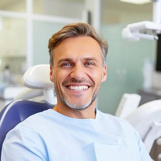Happy dental patient sitting upright in treatment chair