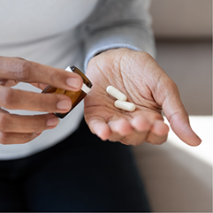 Person taking white pills out of a pill bottle