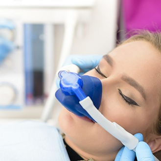 Dental patient with her eyes closed and a nitrous oxide mask over her nose