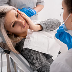 Woman in the dental chair holding the side of her cheek