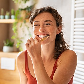 Woman smiling while brushing her teeth