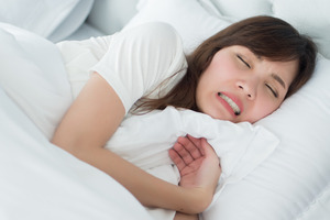 Woman in bed grinding her teeth
