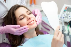 Young woman smiling into mirror in dentist's chair.