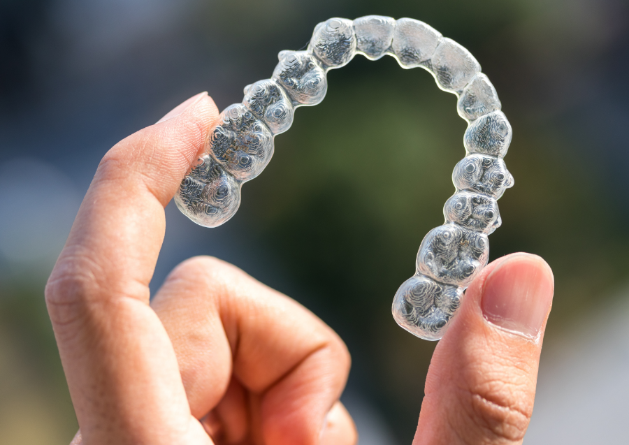 Hand holding Invisalign clear aligner