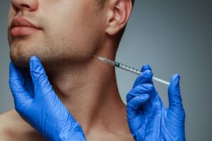 Nose-to-shoulder view of man's profile as gloved hands inject BOTOX into jaw