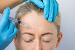 Closeup of woman with graying hair receiving Botox injection in forehead